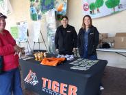 Tiger Sanitation booth at EWL day event with people smiling sharing information and give aways